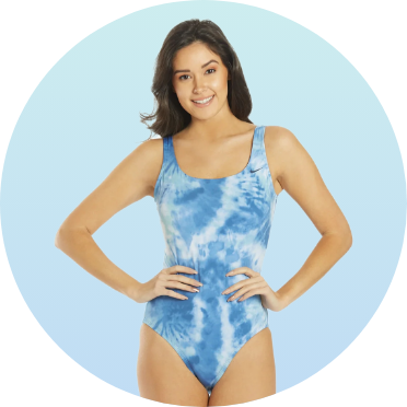 Woman wearing a blue tie-dye one-piece swimsuit, posing with hands on hips. The swimsuit features a scoop neckline and offers a stylish, comfortable fit for swimming.