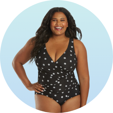 Woman wearing a black one-piece swimsuit with white polka dots, featuring a V-neckline and wrap design. The swimsuit is showcased against a light blue background.