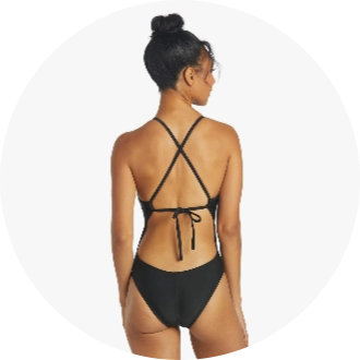 Woman wearing a black one-piece swimsuit with crisscross back straps and tie closure. Ideal for competitive swimming and water activities.