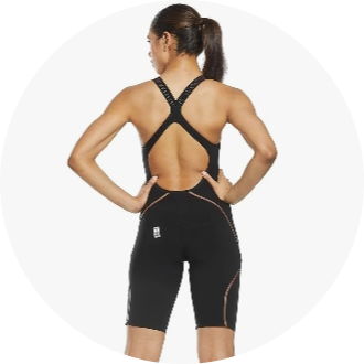 Female swimmer wearing a black racing swimsuit with an open back and cross straps. The suit features sleek design lines and provides a competitive fit for optimal performance.